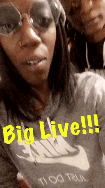 a woman wearing sunglasses and a nike shirt says " big live !!! "