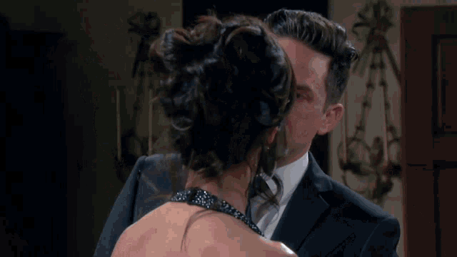 a man in a suit and tie is looking at a woman in a black dress
