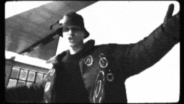 a black and white photo of a man wearing a bucket hat and jacket