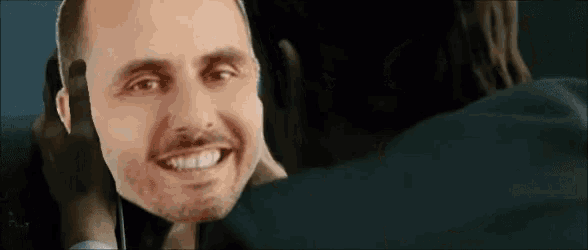 a man with a beard is smiling while another man holds his head .
