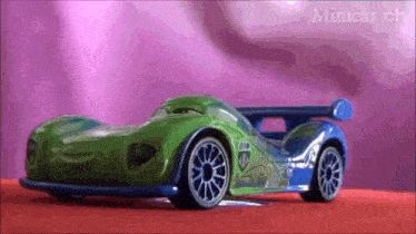 a green and blue toy car on a red surface with the words minicar ch on the bottom