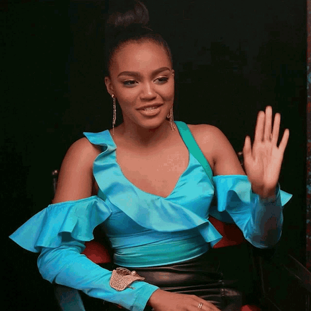 a woman in a blue off the shoulder top is waving
