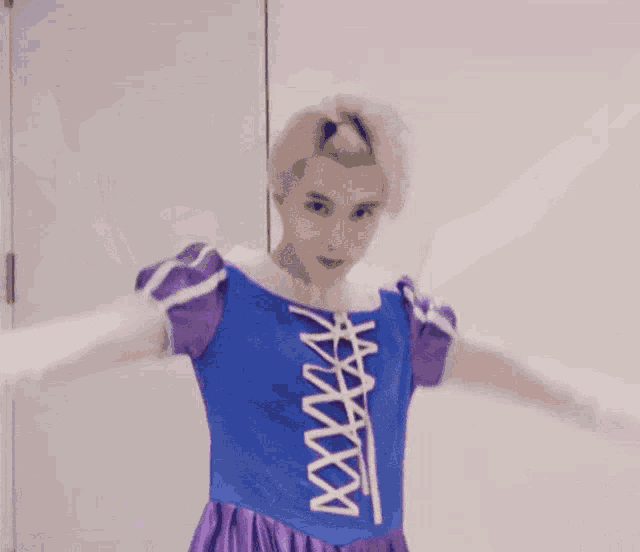 a person in a purple dress is making a heart with their hands