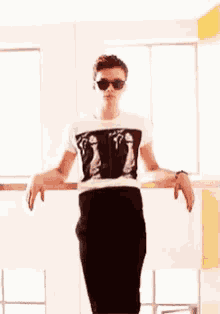 a young man wearing sunglasses and a t-shirt with a picture of a man 's penis on it .