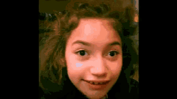 a close up of a girl 's face with a dark background
