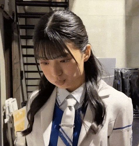 a girl in a suit and tie is standing in front of stairs