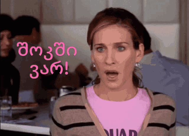 a woman with a surprised look on her face is wearing a pink shirt that says ' quad '