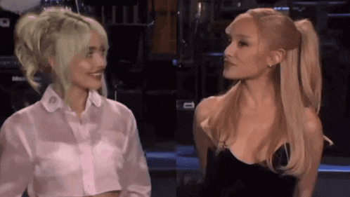 two women with blonde hair are standing next to each other and talking .