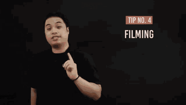 a man in a black shirt is standing in front of a sign that says tip no . 4 filming