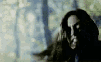 a close up of a woman 's face with a shadow of a person in the background .