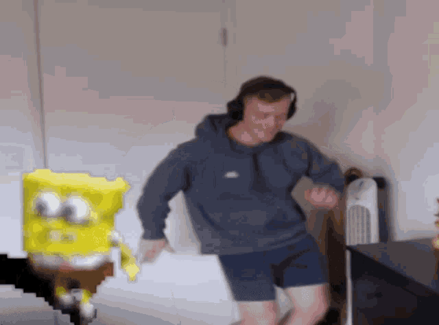 a man wearing headphones is dancing in front of a pixelated spongebob character