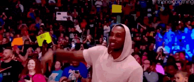 a man in a hoodie is dancing in front of a crowd of people .