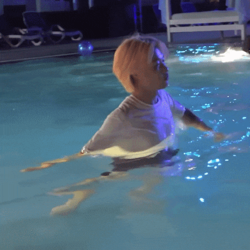 a man in a white shirt is floating in a swimming pool
