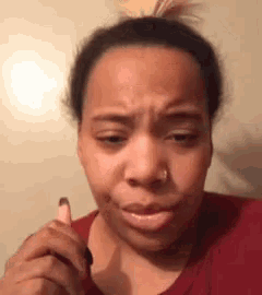 a woman with a nose ring is making a funny face while holding a lipstick .