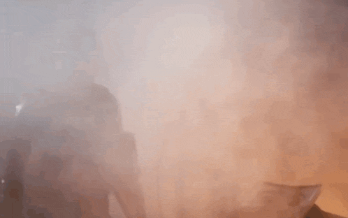 a man with a beard is standing in a foggy room with his hands outstretched .