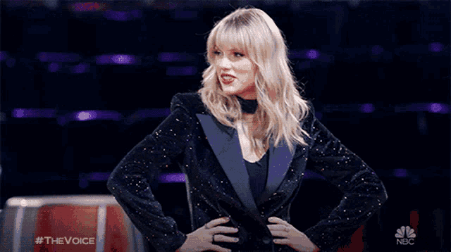 a woman in a tuxedo is standing with her hands on her hips and a nbc logo behind her