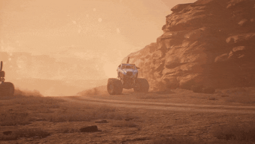 a blue monster truck is driving down a dirt road