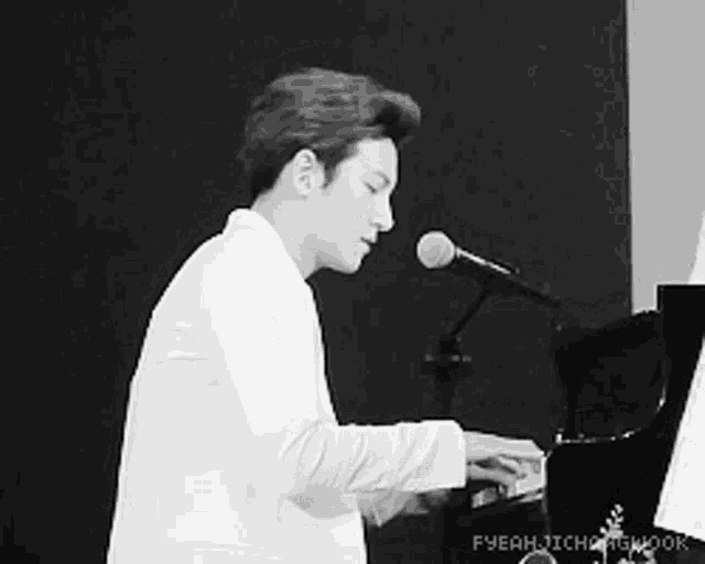 a man in a white suit is playing a piano and singing into a microphone ..