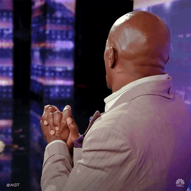 a man in a suit is clapping his hands in front of a screen that says nbc