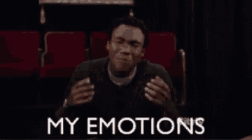 a man is sitting in a theater with a sign that says my emotions on it .