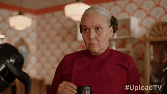a woman in a red shirt is holding a cup of coffee with the hashtag #uploadtv