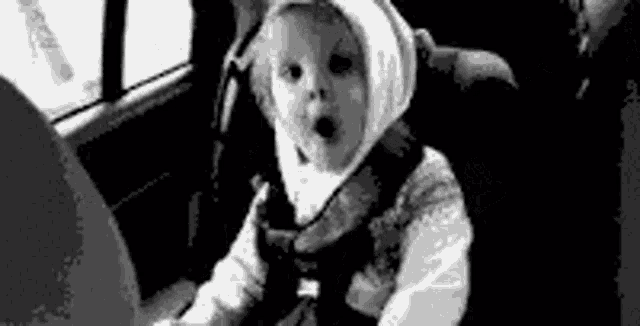 a baby is sitting in a car seat wearing a hood .