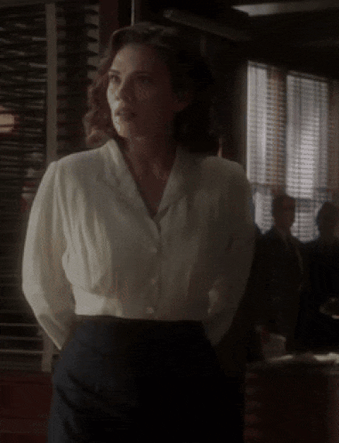 a woman in a white shirt and black pants is standing in a room .
