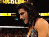 a woman is standing in a wrestling ring with a crowd in the background and a sign that says ' lucha libre '