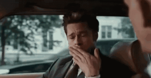 a man in a suit is yawning in the back seat of a car .