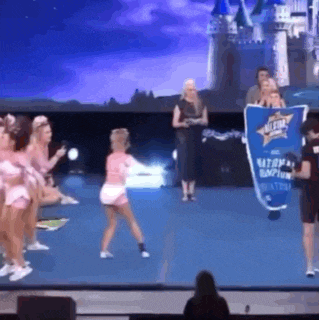 a group of cheerleaders are standing on a stage holding a banner that says national championship .