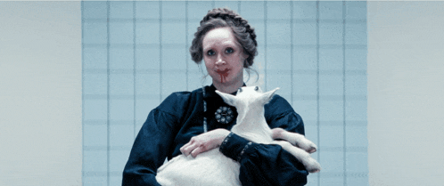 a woman with blood on her face is holding a small white goat