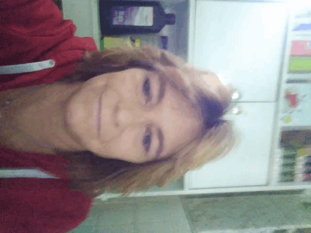 a woman in a red sweatshirt is smiling in front of a bottle that says ' ear drops ' on it