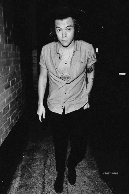 a black and white photo of a man with a tattoo on his chest and a necklace with a cross on it