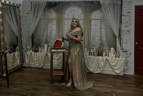 a woman in a long dress is standing in front of a mirror holding a watermelon