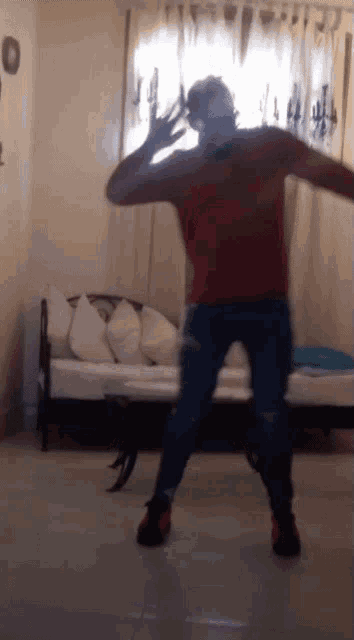 a man in a red sweater is dancing in front of a couch