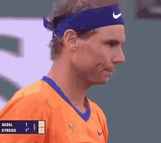 a tennis player wearing an orange shirt and a blue nike headband