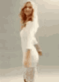 a woman in a white dress and angel wings is standing on a white surface .