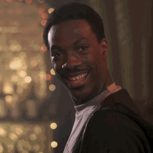 a man with a mustache is smiling and wearing a black jacket