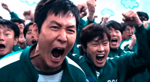 a group of people are screaming with their arms in the air and one of them has the word squid on his shirt