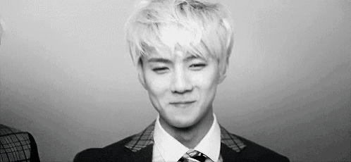 a black and white photo of a man in a suit and tie making a face .