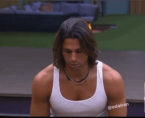 a man with long hair is wearing a white tank top with the hashtag @edaiiran on his arm
