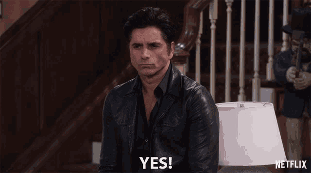 a man in a leather jacket says yes in front of a netflix lamp