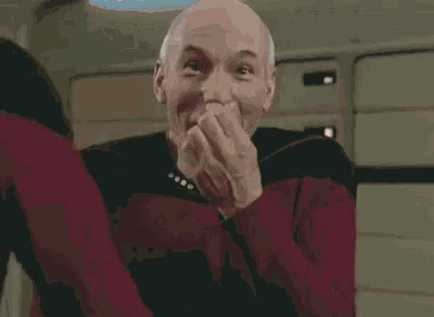 a man wearing a red shirt with a star trek pin