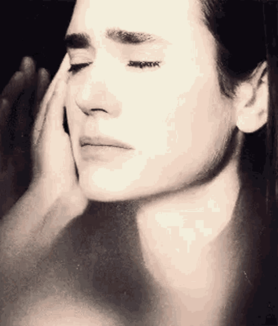 a close up of a woman 's face with her eyes closed and her hand on her face