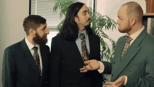 three men in suits and ties are standing next to each other and talking