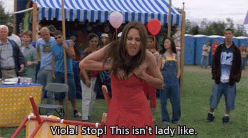 a woman in a red dress is standing in front of a crowd holding her breasts .