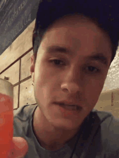 a close up of a man 's face holding a red drink