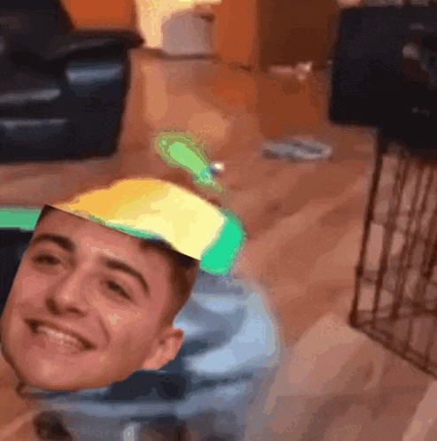 a young man wearing a yellow hat is smiling in a living room