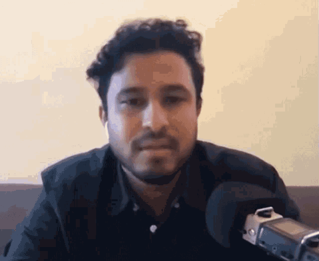 a man with a beard is talking into a microphone .