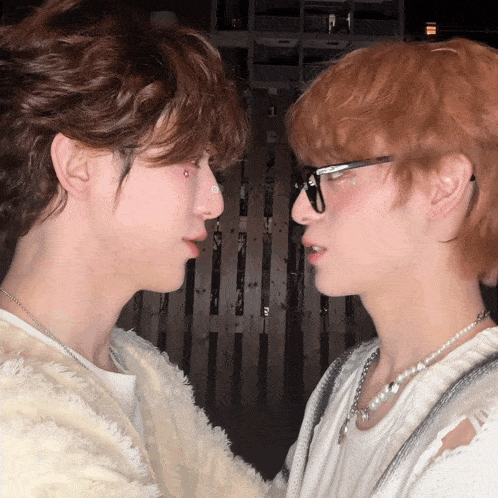 two young men are looking at each other with one wearing glasses